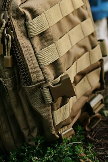 Close-up of a khaki military backpack resting outside, perfect for travel or hiking.